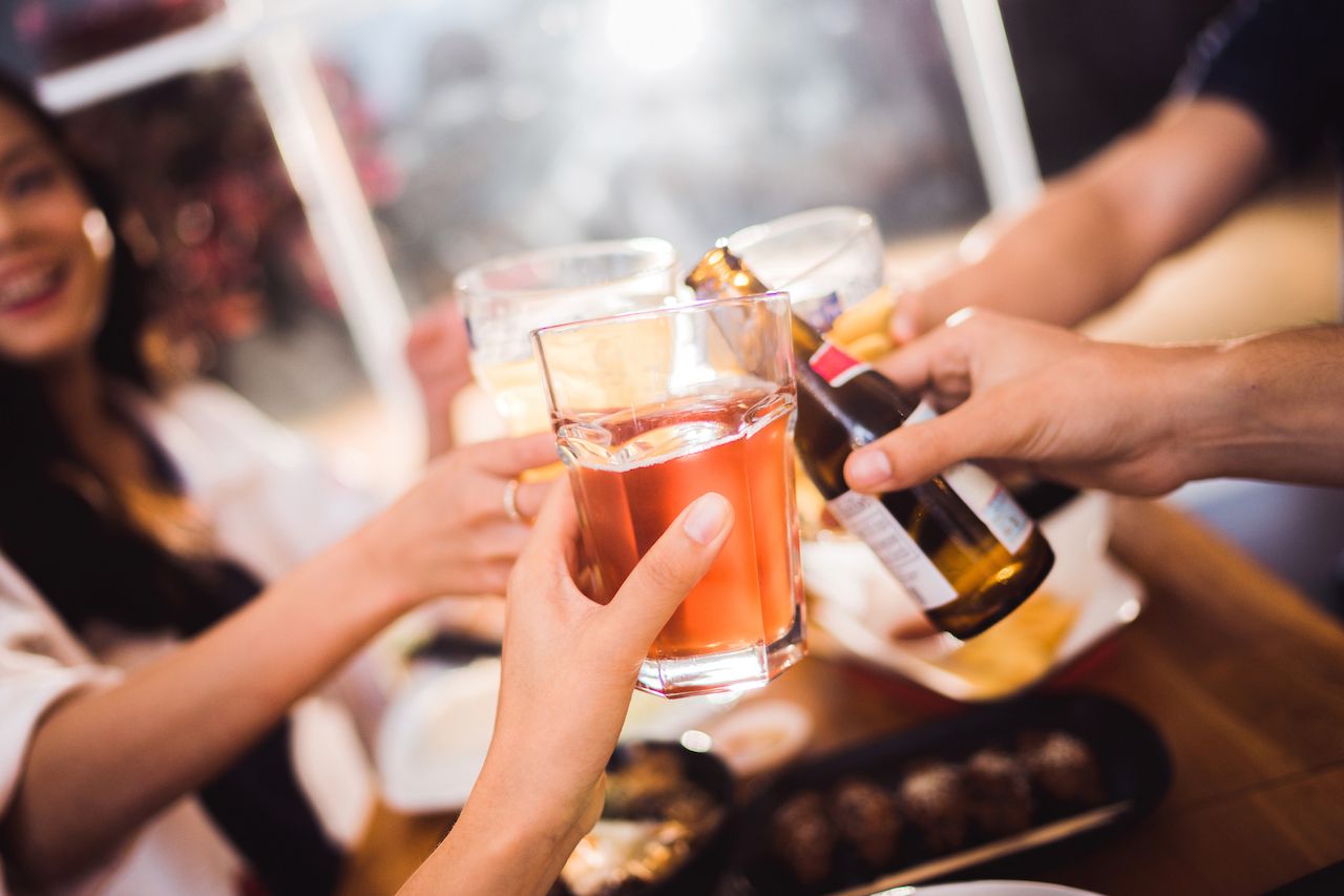 Friends raising drinks together at an evening social gathering
